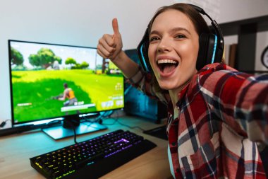 Heyecanlı kız oyun oturma masada bir selfie alarak online oyun kapalı, bir bilgisayarda oynamak