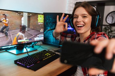 Heyecanlı kız oyun oturma masada bir selfie alarak online oyun kapalı, bir bilgisayarda oynamak