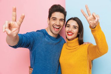 Genç çift ayakta iki renkli arka plan, gösteren barış hareketi izole