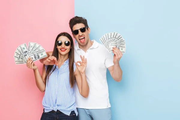 Entusiasmado Jovem Casal Isolado Sobre Dois Fundos Coloridos Mostrando Notas — Fotografia de Stock