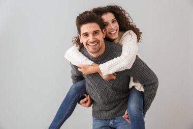 Görüntü beyaz çift eğleniyor ve neşeli kadın gri arka plan üzerinde izole piggybacking adam