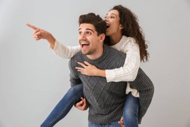 Görüntü mutlu çiftin eğleniyor ve genç kadın gri arka plan üzerinde izole piggybacking adam