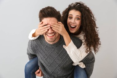 Görüntü heyecanlı çift eğleniyor ve gri arka plan üzerinde izole kız arkadaşı piggybacking adam