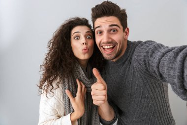 Neşeli adam ve selfie fotoğraf çekme ve gri arka plan üzerinde izole parmaklarıyla işaret kadın portresi