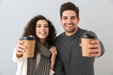 Paket servisi olan restoran kahve fincanı gösterilen gri arka plan üzerinde izole ayakta kazak giyen çift