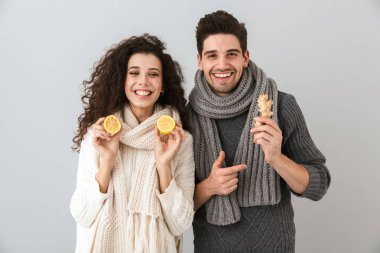 Sağlıklı iki adam ve limon ve gri arka plan üzerinde izole zencefil tutan tulum giyen kadın fotoğrafı