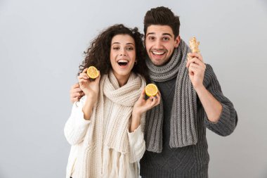 Çift erkek ve limon ve gri arka plan üzerinde izole zencefil tutan tulum giyen kadın fotoğrafı