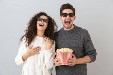 Mutlu bir adam ve 3d gözlük ile pop corn gri arka plan üzerinde izole kova tutarak giyen kadın görüntüsü