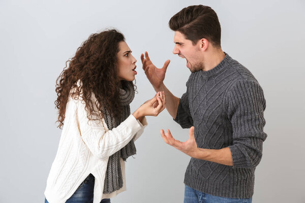 Photo of angry man and woman screaming at each other standing face to face isolated over gray background
