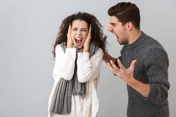 Photo of annoyed man and woman screaming while fighting together isolated over gray background