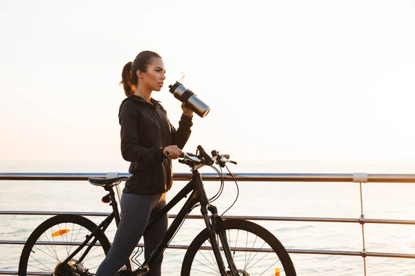 Foto Mujer Caucásica Bebiendo Agua Mientras Monta Bicicleta Paseo Marítimo — Foto de Stock