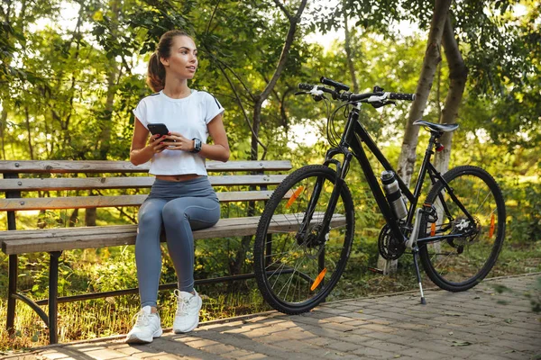 Imagen Mujer Caucásica Sentada Banco Parque Con Bicicleta Uso Teléfono — Foto de Stock