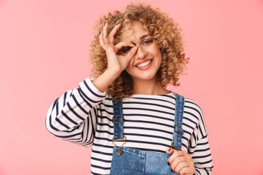 Fotoğraf esmer kıvırcık kadın 20'li yaşlarda ok gülümseyen ve gösterilen işareti üzerinde pembe arka plan izole kamera