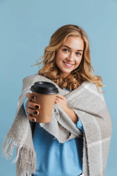 可爱的女人20多岁的图像包裹在毯子里 拿着外卖咖啡 在蓝色的背景中被隔离 — 图库照片
