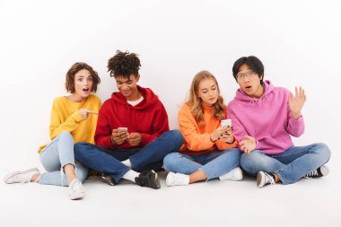 Cep telefonunu kullanarak beyaz bitti, izole grup neşeli çok ırklı arkadaşıyla oturan