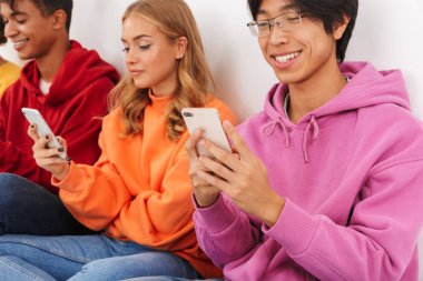 Cep telefonları holding beyaz bitti, izole grup neşeli çok ırklı arkadaşıyla oturan