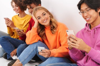 Cep telefonları holding beyaz bitti, izole grup neşeli çok ırklı arkadaşıyla oturan