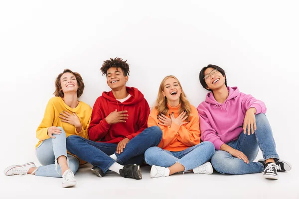 Üzerinde beyaz izole oturan, gülüyor neşeli çok ırklı arkadaş grubu