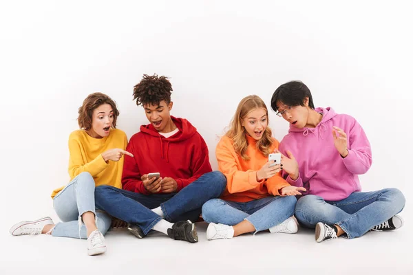 Grupo Alegres Amigos Multirraciales Sentados Aislados Sobre Blanco Usando Teléfonos — Foto de Stock