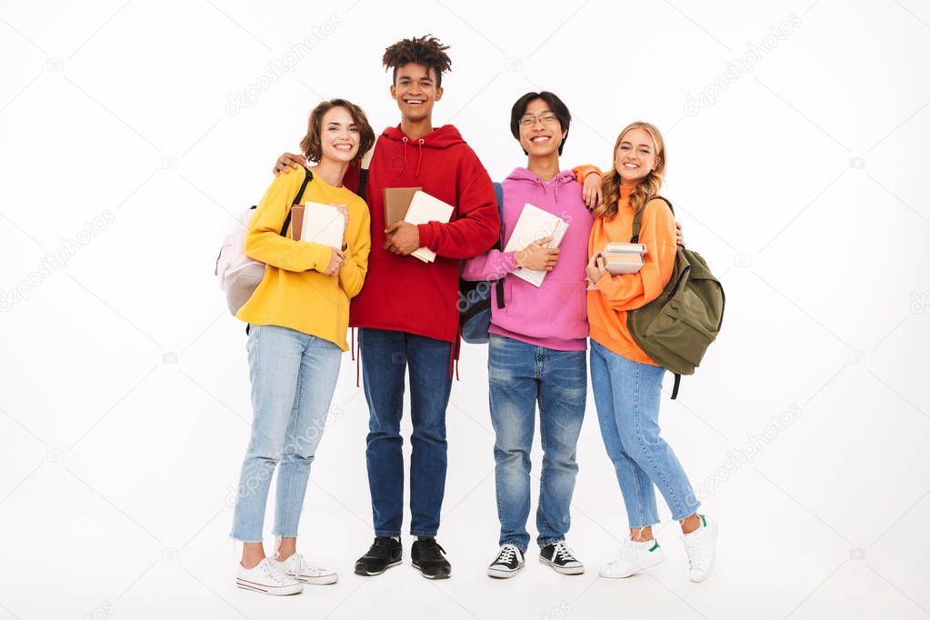 Group of cheerful teenagers isolated over white background, carrying backpacks, holding books