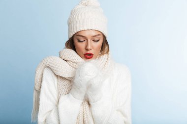 Isınma kadar kazak ve üzerinde mavi arka plan, izole şapka giyen genç kadın dondurulmuş