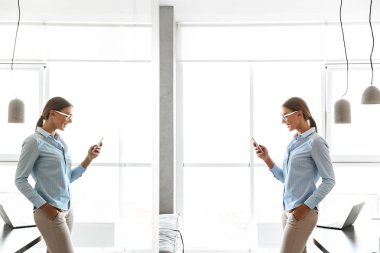 Gülümseyen genç işkadını cep telefonuyla duran bir mutfak