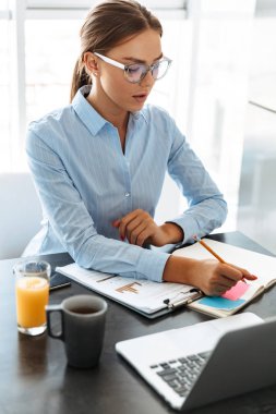 Kendine güvenen iş kadını mutfakta otururken dizüstü bilgisayarda çalışma