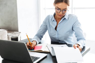 Kendine güvenen iş kadını mutfakta otururken dizüstü bilgisayarda çalışma