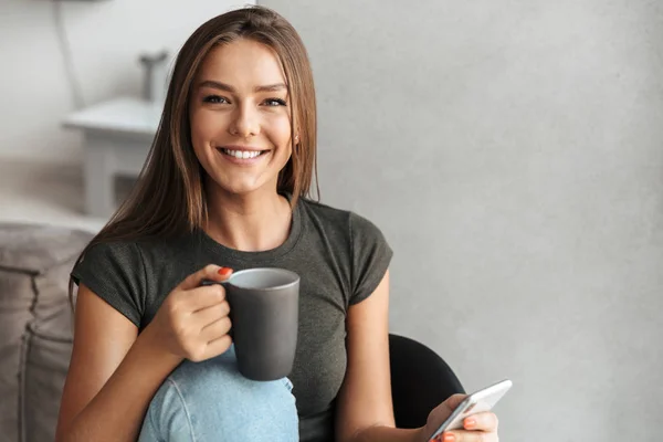 Happy Young Woman Sitting Couch Drinking Tea Using Mobile Phone — Stock Photo, Image