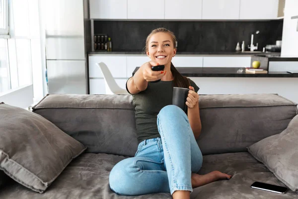 Cheerful Young Woman Sitting Couch Home Changing Channels Drinking Tea — Stock Photo, Image