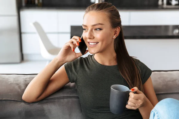 Cheerful Young Woman Talking Mobile Phone While Sitting Couch Home — Stock Photo, Image
