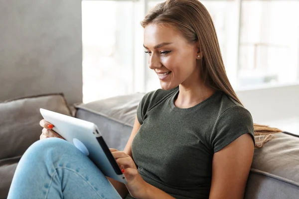 Leende Ung Kvinna Sitter Soffa Hemma Med Hjälp Tablet — Stockfoto