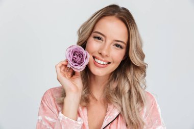 Güzel genç sarı saçlı kadın gri arka plan üzerinde izole, bir çiçek tutarak, poz