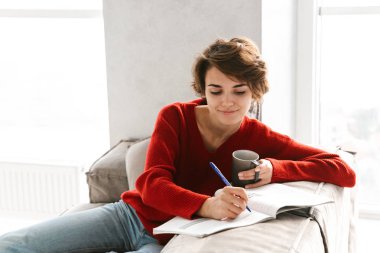 Neşeli kız evde bir kanepede döşenmesi ve çay içme eğitim