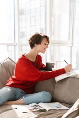 Neşeli kız evde bir kanepede döşenmesi ve çay içme eğitim