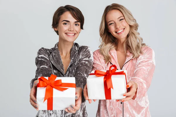 Dos Chicas Guapas Usando Pijamas Aisladas Sobre Fondo Gris Sosteniendo — Foto de Stock