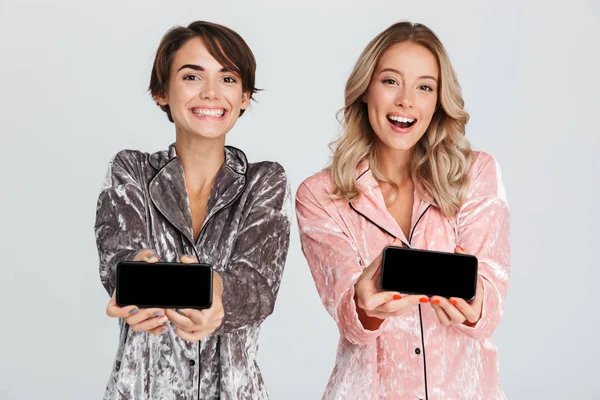 Gri arka plan üzerinde izole pijama giymiş iki güzel kızlar