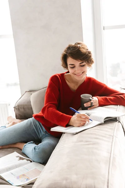 Chica Alegre Estudiando Casa Mientras Acuesta Sofá Beber — Foto de Stock