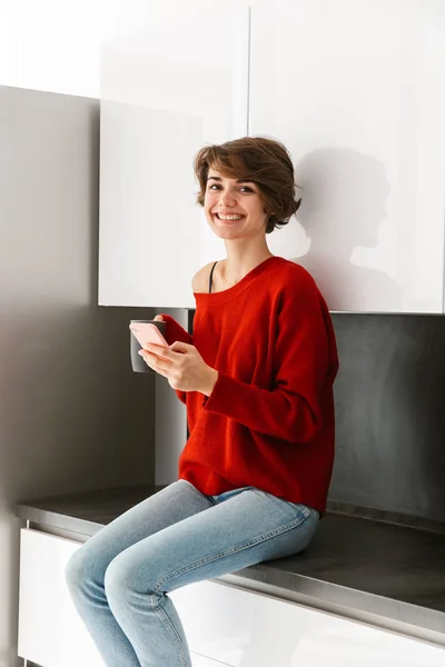 Mujer Joven Sonriente Usando Suéter Sentado Una Mesa Cocina Casa — Foto de Stock