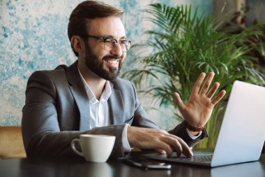 Yakışıklı genç işadamı kafede kapalı oturan bir dizüstü bilgisayar üzerinde çalışan takım elbise giymiş