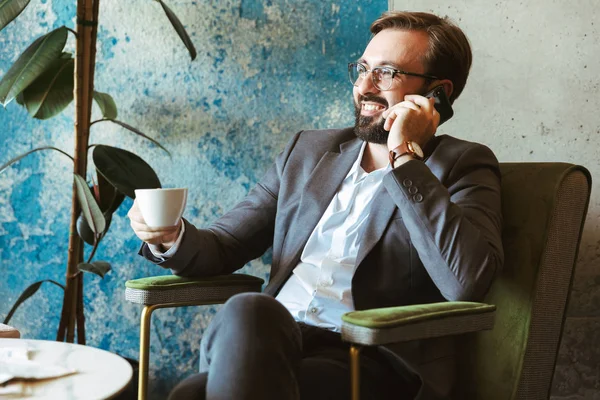 Χαμογελώντας Επιχειρηματίας Φορώντας Κοστούμι Μιλάμε Στο Κινητό Τηλέφωνο Ενώ Κάθεται — Φωτογραφία Αρχείου