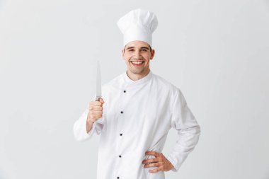 Happy chef cook wearing uniform holding a knife isolated over white background