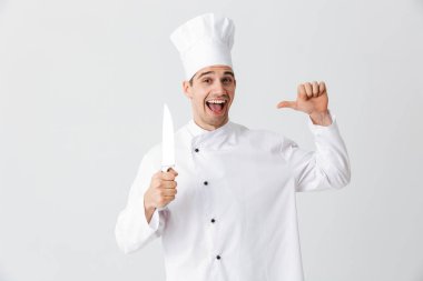 Happy chef cook wearing uniform holding a knife isolated over white background