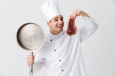 Giyen üniforma gösteren ham sığır eti biftek kızartma tavası beyaz arka plan üzerinde izole holding neşeli Şef aşçı