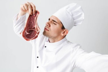 Bir selfie alarak giyen üniforma gösteren ham sığır eti biftek beyaz arka plan üzerinde izole neşeli Şef aşçı