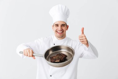 Baharat beyaz arka plan üzerinde izole pişmiş sığır eti biftek ile Tekdüzen gösteren kızartma tavası giyen neşeli Şef aşçı