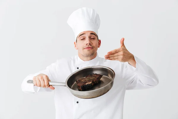 愉快的厨师厨师穿着制服显示煎锅与熟牛排隔离在白色背景 调味料 — 图库照片
