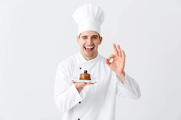 Cheerful Chef Cozinheiro Vestindo Uniforme Mostrando Pastelaria Uma Placa Isolada — Fotografia de Stock