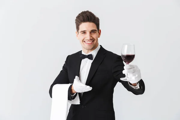 Красивий Молодий Офіціант Тукседо Тримає Келих Червоного Вина Ізольовано Сірому — стокове фото