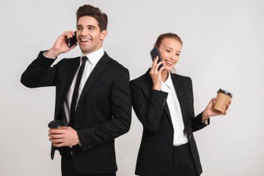 Kendine güvenen genç iş kaç paket servisi olan restoran kahve holding, cep telefonunu kullanarak, konuşmak gri arka plan üzerinde izole ayakta